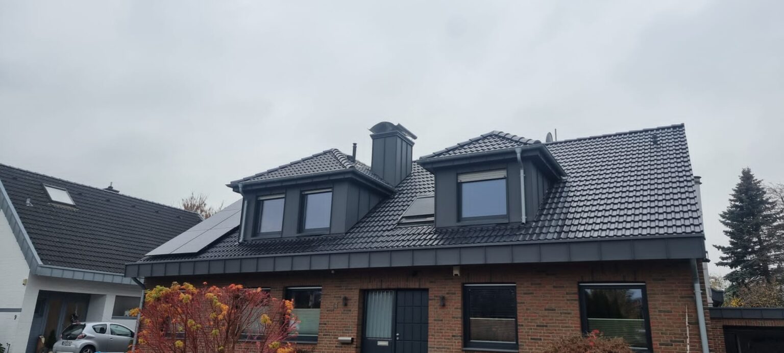 Ein saniertes Doppelhaushälften-Steildach mit zwei sanierten Dachgauben, einem sanierten Kamin und einer PV-Anlage